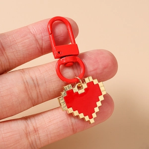 Macro detail of red pixel heart keychain with gold edges and red lobster clasp charm