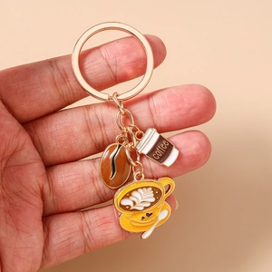 Close-up of enamel coffee charms including beans and cups on a gold keychain