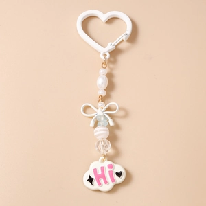 Détail de porte-clés perlé avec nœud blanc et pendentif nuage portant le message rose HI