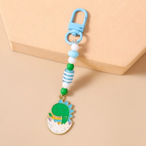 Close-up of cute green dinosaur egg charm with colorful beads and light blue carabiner