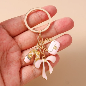 Close-up of pink ballet shoe and handbag charms on a gold rhinestone keychain