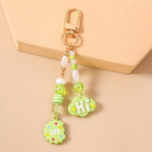 Detail of beaded keychain with cookie charm and cloud pendant on soft beige background