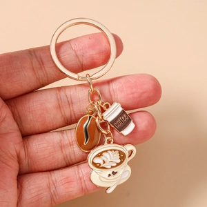 Close-up of enamel coffee bean and cup charms on a golden metal keychain set