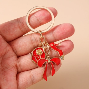 Detail of gold keychain with red bow charm, rhinestone high heel and engraved love medal