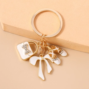 Detailed view of golden alloy keychain with rhinestone bow handbag and ballet shoes charms