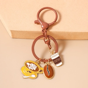 Detail of coffee-themed keychain with yellow latte cup, coffee bean and brown paper cup