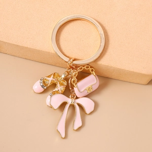 Close-up of pink enamel ballet shoes and handbag charms on a gold keychain