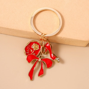 Detail showing red high heel charm and rose love tag on a gold keychain pendant