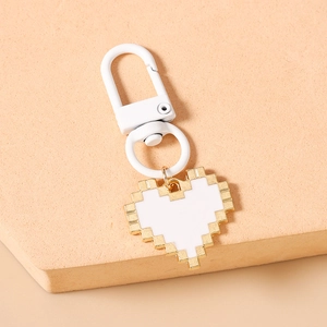 Detail of pixel heart keychain with gold plating and white lobster clasp on stone stand