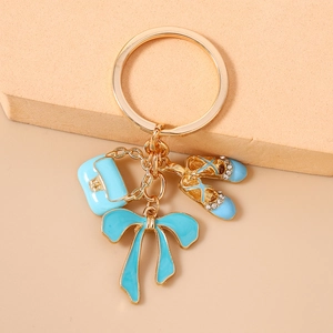 Detail of light blue enamel gold keychain with rhinestone ballet shoes and bow charms