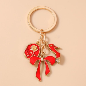 Close-up of gold keychain with red rose LOVE tag, enamel bow, and rhinestone high heel