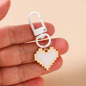 Close-up of pixelated heart keychain with white enamel inlay and golden alloy edges