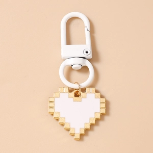 Close-up of pixel art heart keychain with gold metal frame and white enamel filling