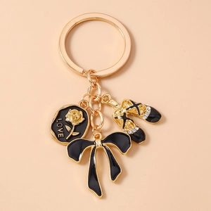 Detail of metal keychain with black rose pendant, golden bow, and rhinestone ballet shoes