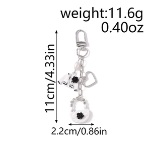 Detail view of heart keychain featuring a mini jacket, handbag, and pearl charm