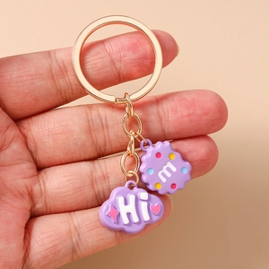 Detail of purple cloud and wave charm keychain with golden metal ring held in hand