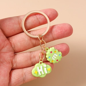 Detail of green cloud and biscuit charm keychain with Hi and m lettering on gold ring