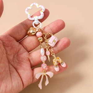 Dettaglio di un portachiavi rosa con cuore dorato e ciondoli a ballerina tenuto in mano