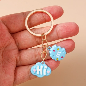 Close-up of light blue cloud and biscuit pendants on a gold-tone keyring charm