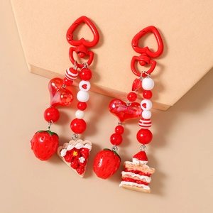 Beaded heart keychain featuring realistic strawberry cake charms on beige stand
