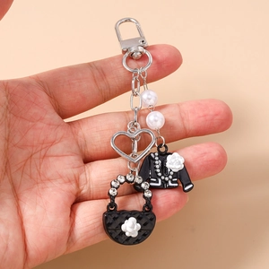 Detail view of heart keychain with faux pearls, enamel handbag, and jacket charms