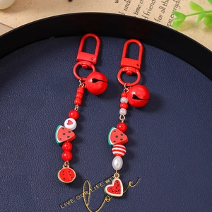 Detailed macro view of beaded watermelon charms with red bells and spring metal hooks