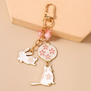 Detail of cherry blossom keychain with rabbit, cat charms and pink beads on gold hardware