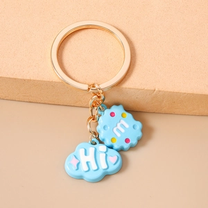 Close-up of blue cloud pendant keychain with m letter biscuit charm and golden ring