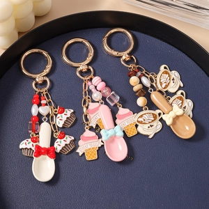 Dessert and coffee themed keychains with beaded charms and gold rings on blue tray