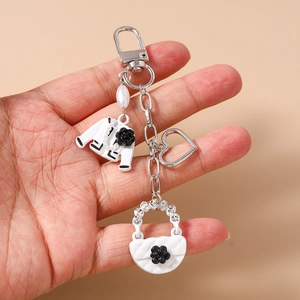 Detailed close-up of heart clasp with enamel jacket and handbag charms on a keychain