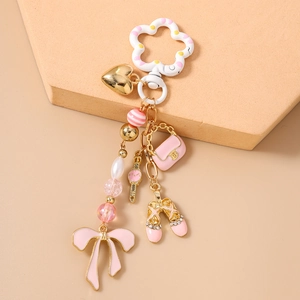 Dettaglio dei ciondoli rosa e oro con scarpetta da ballo e cuore sul portachiavi