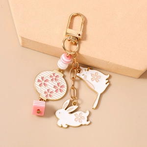Detail of pink and white enamel cherry blossom cat and rabbit charms with golden clasp