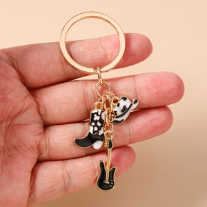 Detail of western cow print boots, cowboy hat and guitar pendants on golden keychain