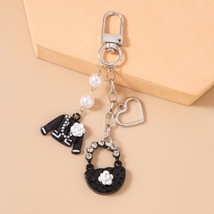 Detail of beaded heart keychain with black jacket and handbag charms on orange background