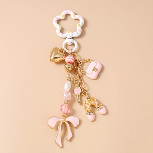Dettaglio portachiavi con fiocco rosa, ciondoli a cuore dorato e accessori per ballerina