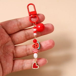 Detail of red watermelon beaded keychain featuring a metal lobster clasp and small bell charm