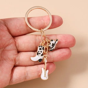 Detail of keychain featuring mini cowboy boot, hat and guitar charms in cow print