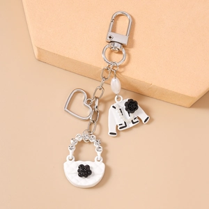 Detailed view of fashion keychain with white jacket charm, heart and pearl bag pendant