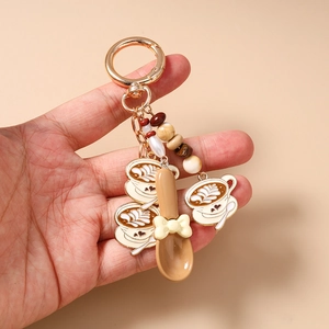 Detail of coffee theme keychain with latte art charms and a small decorative spoon