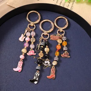 Western cowboy style keychains with guitar boots and hat charms on a metal tray