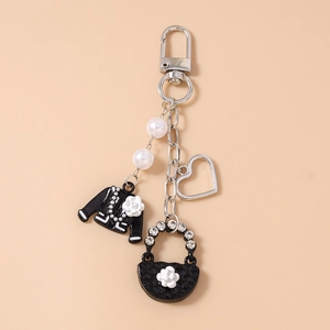 Detail of beaded keychain with black jacket, quilted bag charms and white camellia flowers