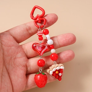 Detail of handmade beaded keychain featuring a realistic strawberry cake and red heart clasp