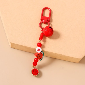 Detailed shot of a red bead keychain featuring a bell and watermelon charms on a stand