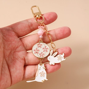 Detail of hand holding Japanese Sakura keychain with cat, rabbit and lantern charms