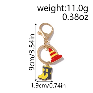 Detail view of ambulance keychain featuring traffic cone and rain boots charm on gold clasp