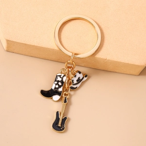 Detail of Western cowboy keychain with guitar, boots and hat charms on a gold ring
