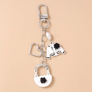 Close-up of stylish silver keychain with camellia suit, handbag and heart charms
