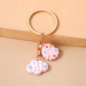 Detail of pink cloud and biscuit charms on a gold keychain with "Hi" and "m" letters
