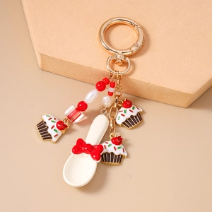 Detail of sweet coffee spoon keychain with red bow, cupcakes and golden lobster clasp