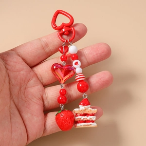 Detailed close-up of a red strawberry cake pendant with heart-shaped beaded keychain